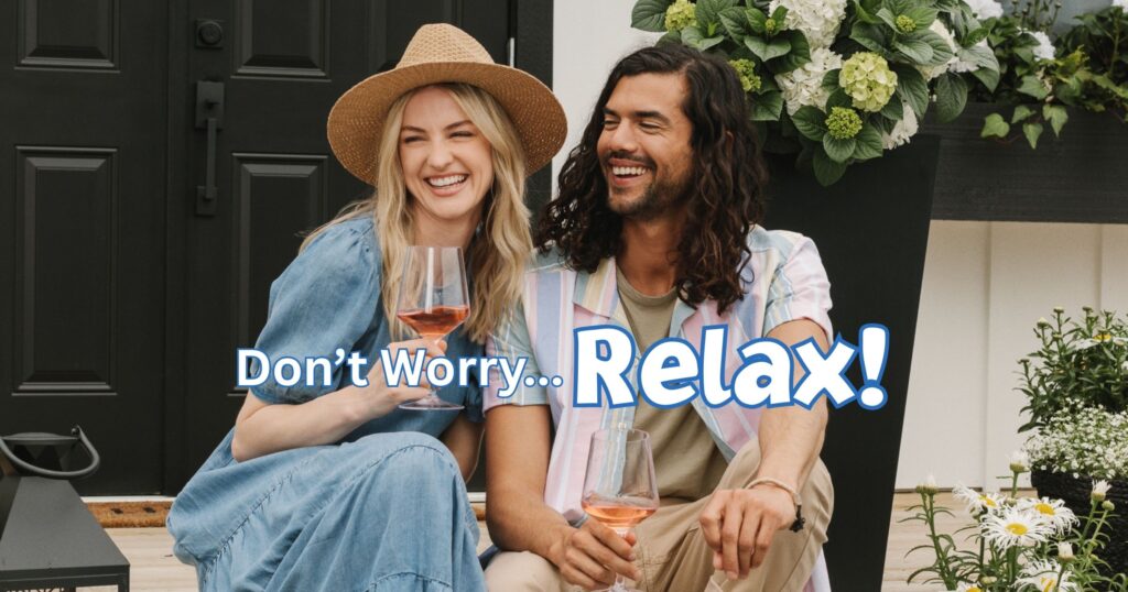 Couple relaxing with wine outside, surrounded by flowers.